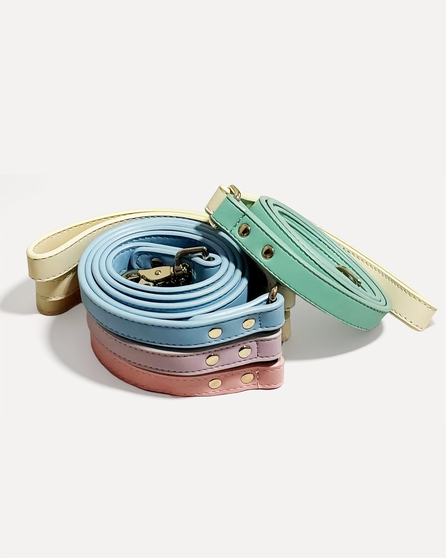 Stack of eco-friendly, two-tone genuine leather dog leashes in pastel colors.