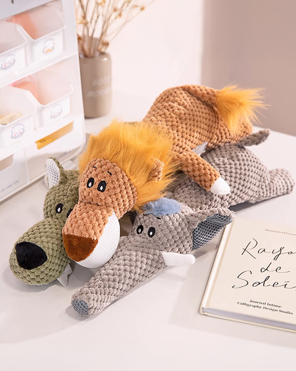 Three plush squeaky dog toys—a lion, a wolf, and a fox.