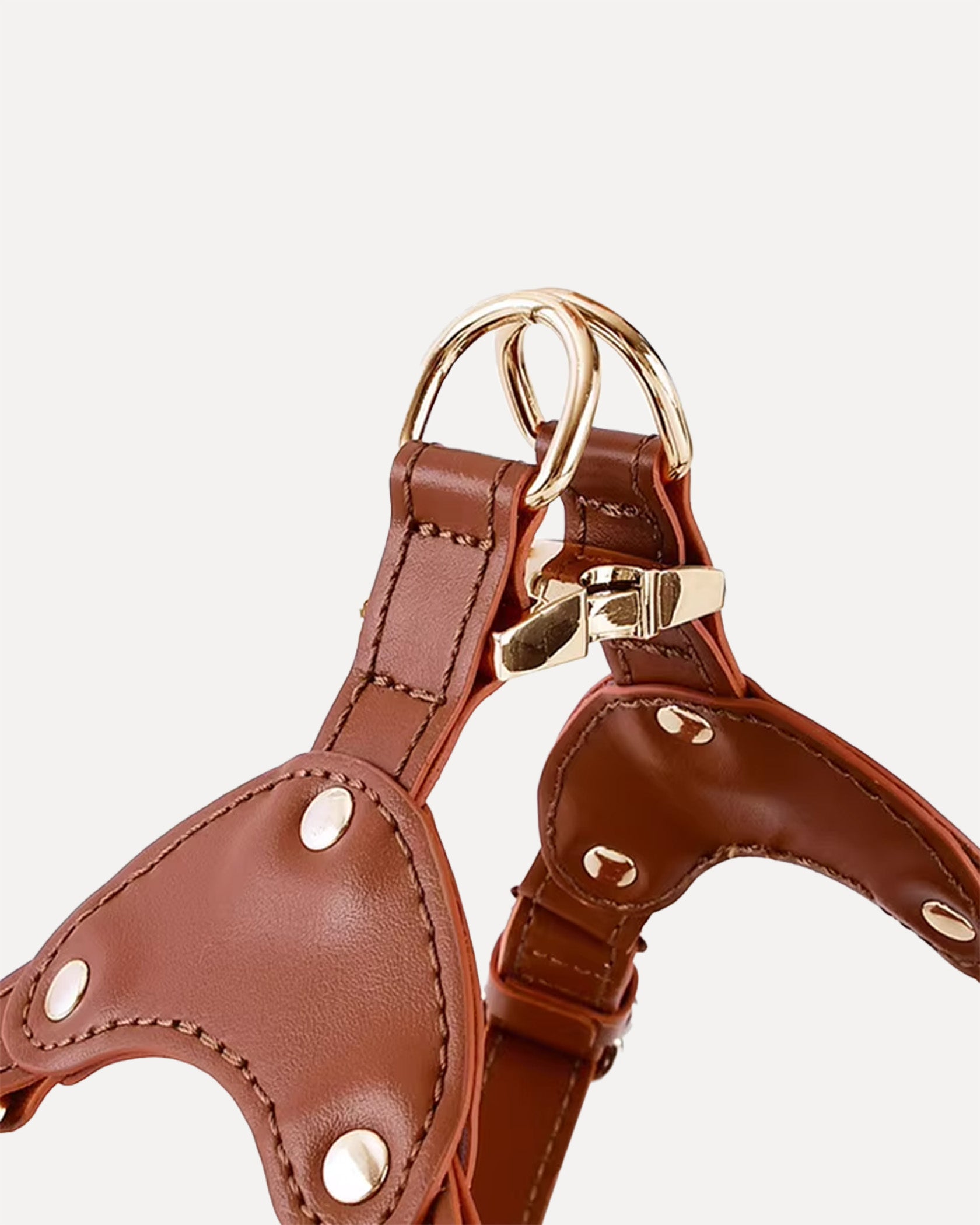 Detail view of a brown waterproof soft leather dog harness with gold-tone D-rings and buckle, highlighting reinforced stitching and hardware.