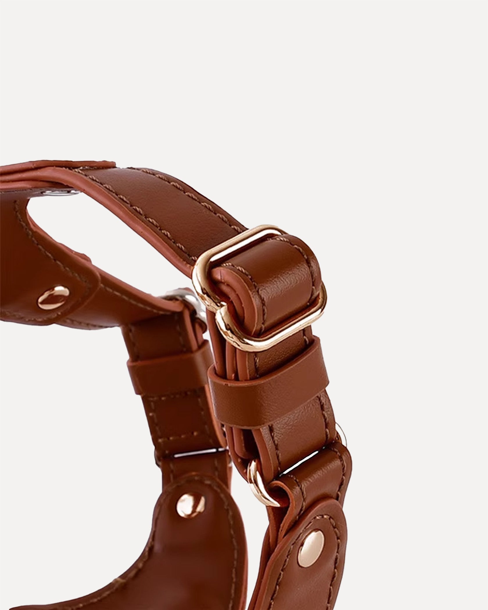 Close-up of a brown waterproof soft leather dog harness with adjustable straps and gold-tone metal buckle.